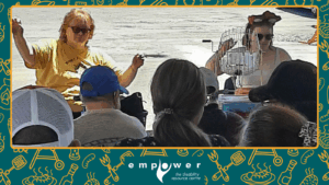 Empower N L Executive Director Kathy Hawkins calls bingo at our Annual Members' Barbecue, with help from summer student Claudia. The Empower N L logo is centered at the bottom.