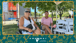Two Empower N L members (one using a wheelchair) sit under the tent at our Annual Members' Barbecue. The Empower N L logo is centered at the bottom.