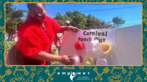 Empower N L volunteer Joy demonstrates the Carnival Punch Out game. The Empower N L logo is centered at the bottom.