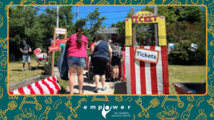 Empower N L members head into the back yard carnival, past the "ticket booth" and red and white striped decorations. The Empower N L logo is centered at the bottom.