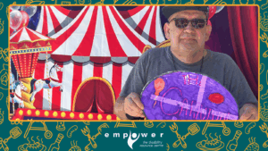 An Empower N L member poses in front of the carnival wall. The Empower N L logo is centered at the bottom.